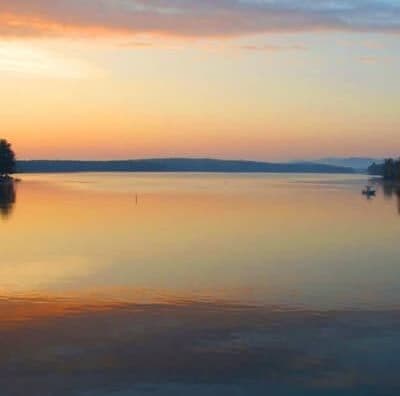 A serene lake at sunset reflecting soft pastel colors in the water.